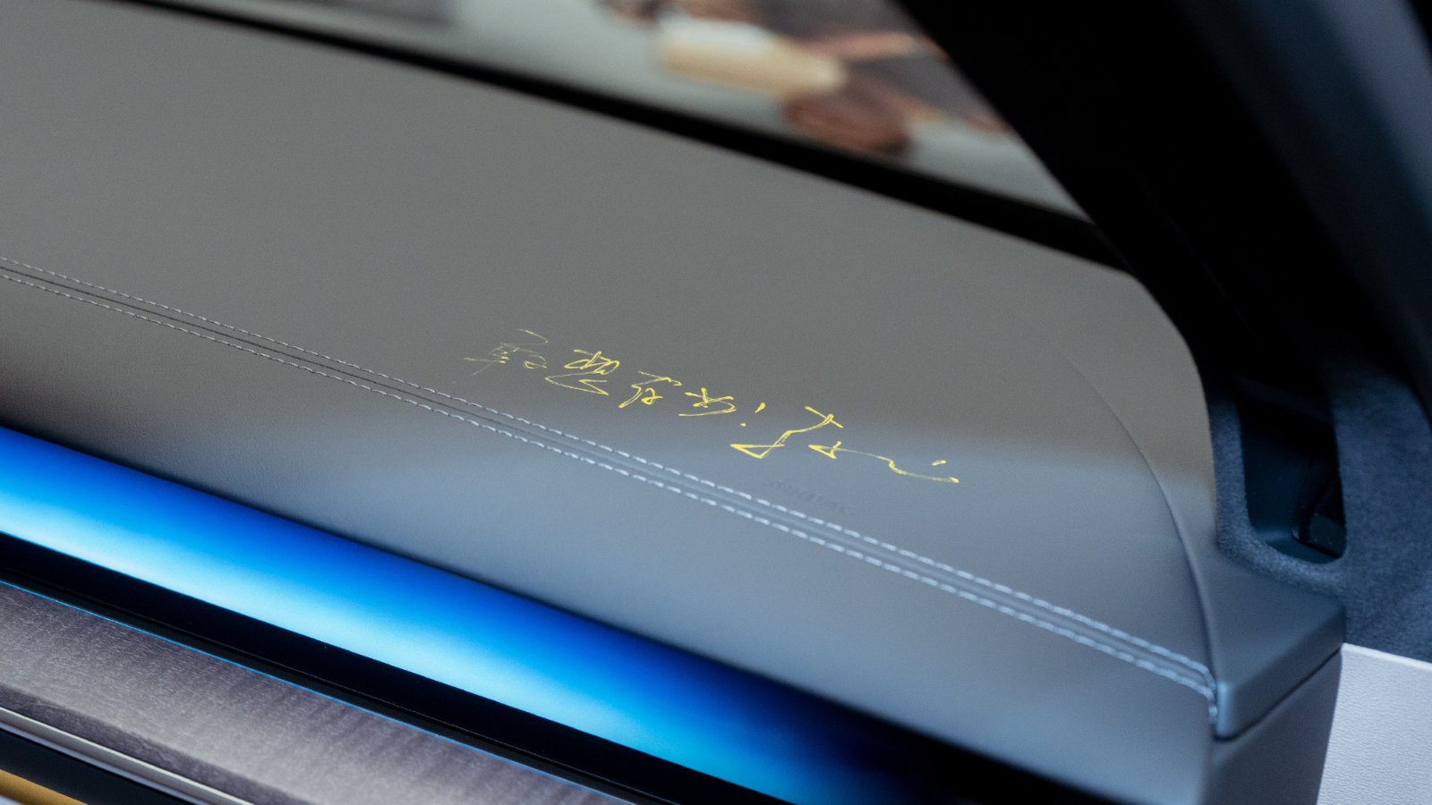 A gold handwritten inscription on the Nio ES9's gray interior trim above a blue ambient light strip.
